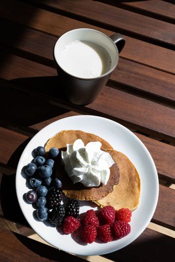 top view of pancakes with cream, blueberries and grapes with a glass of milk. Healthy food
