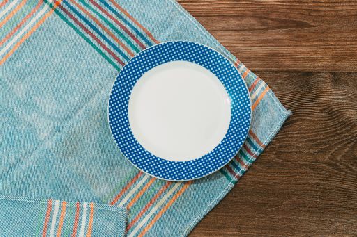 A top view of a plate with blue patterns placed on a table cloth on a wooden surface