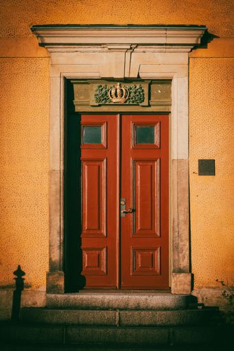 A vertical shot of an old wooden door and entrance with a crown symbol