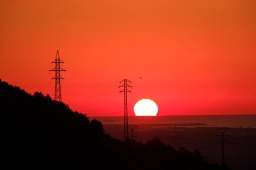 A beautiful shot of hills and transmission towers under the red sky during sunset
