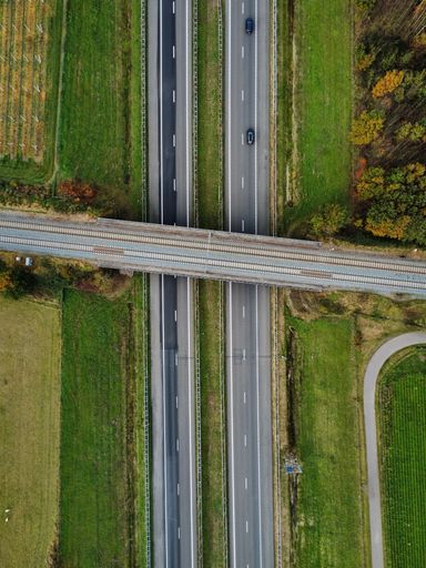 A vertical aerial top view shot of two roads and a bridge over them in a field