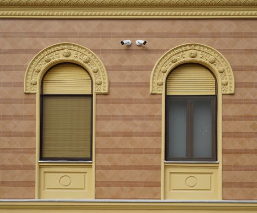 A closeup shot of windows with opened and closed shutters on the renovated yellow building