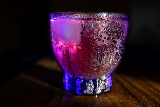 A closeup of a glass of a cold cocktail on a wooden table. Nightclub drink.