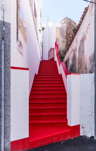 A vertical shot of the red-colored staircase between the white building