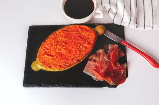 slice of bread with tomato, iberian ham and a cup of coffee typical spanish lunch on a black board with a white background