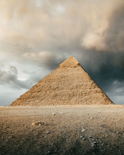 A vertical shot of the Great Pyramid of Giza with fluffy clouds in the sky