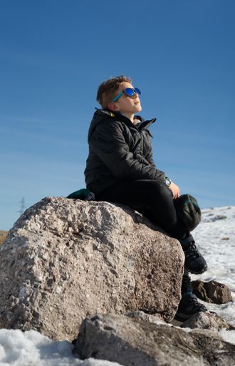 A vertical shot of a Caucasian boy playing with snow