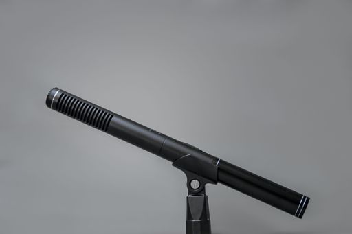 A closeup of a professional black metal microphone for recording on gray background