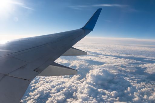 A closeup shot of a wing of an airplane flying above the morning clouds