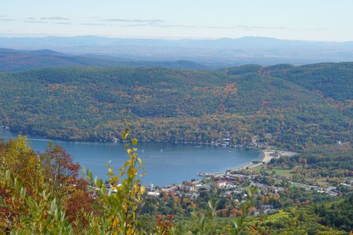 An aerial view of a lake surrounded by dense colorful forests in autumn