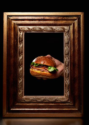A vertical shot of a person holding a burger through a vintage wooden frame