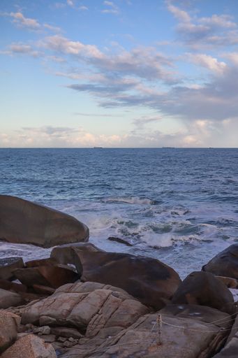 A vertical shot of the rocky seashore under a bright sky on Shanwei Beach