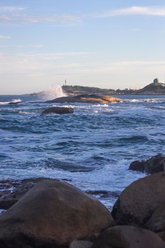 A vertical shot of the rocky seashore under a bright sky on Shanwei Beach
