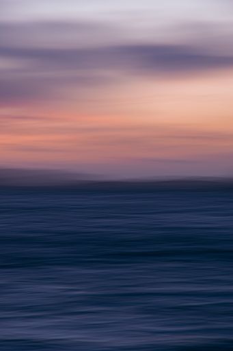 A long exposure vertical shot of sunset cloudy sky over the sea
