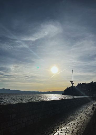 A vertical shot of a bright sun shining over the bridge