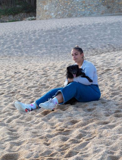 Young woman playing on the beach with her cute black dog named Loki. Running, smiling, loving and hugging each other in happy attitude and enjoying