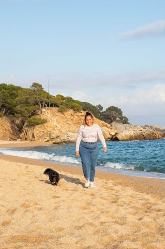 Young woman playing on the beach with her cute black dog named Loki. Running, smiling, loving and hugging each other in happy attitude and enjoying