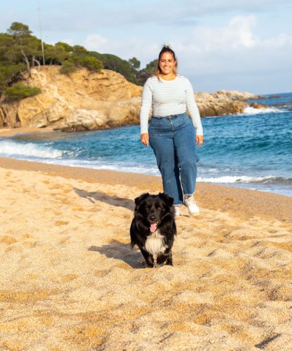 Young woman playing on the beach with her cute black dog named Loki. Running, smiling, loving and hugging each other in happy attitude and enjoying