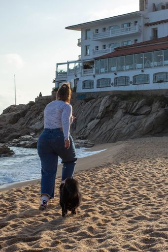 Young woman playing on the beach with her cute black dog named Loki. Running, smiling, loving and hugging each other in happy attitude and enjoying a
