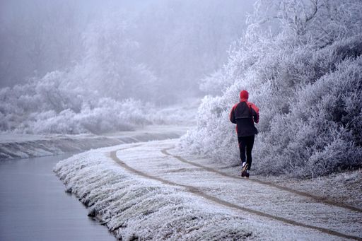 A closeup shot of a young man running near the lake in the forest in winter