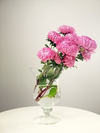 A vertical shot of a bouquet of pink chrysanthemums in a vase on the table