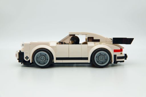 A LEGO car with a LEGO minifigure figure driver placed in front of it