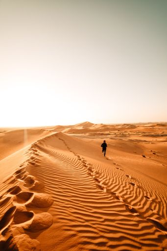 A man running on a sand dunes during a sunny day
