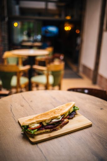 A vertical selective focus shot of a grilled sandwich on a wooden board