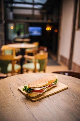 a vertical shot of an isolated hot dog with tomatoes on a wooden table