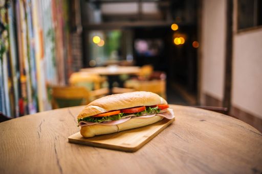 A view of a delicious looking sandwich with tomato and am on a wood board on a wooden table
