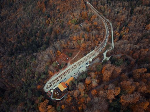 An aerial shot of a train station in Switzerland surrounded by a forest for cool autumn background