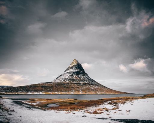 A scenic view of snowy field, river and mountain landscape in Kirkjufell, Iceland
