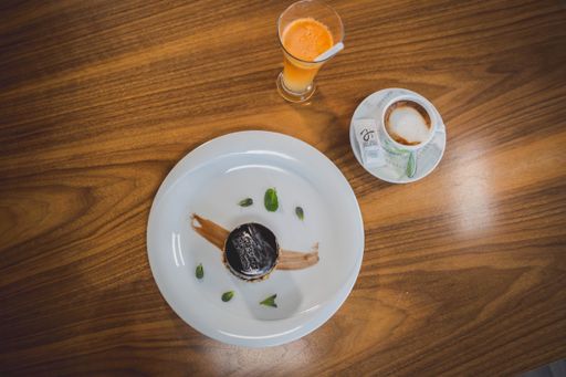 A top view of a dark chocolate cake served with a cup of coffee and fresh orange juice in a cafe
