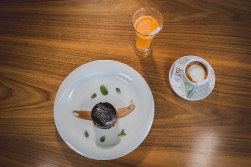A top view of a dark chocolate cake served with a cup of coffee and fresh orange juice in a cafe