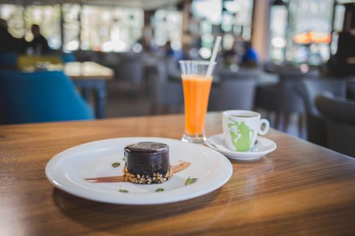 A delicious dark chocolate cake served with a cup of coffee and fresh orange juice in a restaurant