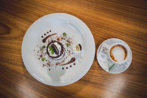 A top view of a no-bake small cheesecake served with a cup of hot coffee on a wooden table