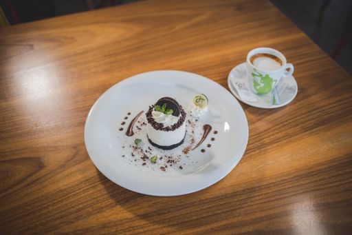 A high angle shot of a no-bake small cheesecake served with a cup of hot coffee on a wooden table