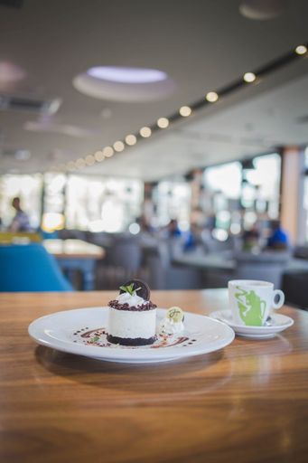 A vertical shot no-bake small cheesecake served with a cup of coffee in a cozy restaurant