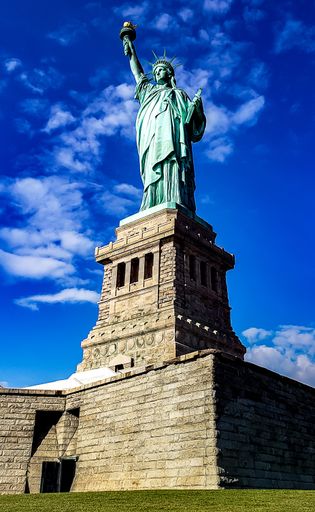A vertical low angle shot of the Statue of Liberty on a cloudy day