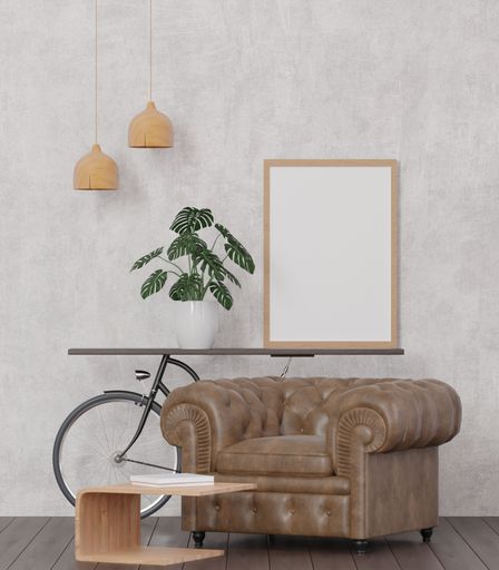 A 3d rendering of a loft-style living room with a concrete wall, bicycle, mockup frame, and plant.