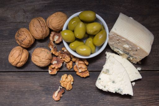 roquefort cheese with walnuts and olives on dark background