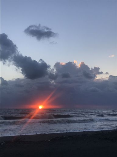 A vertical shot of the sun setting in the cloudy sky over the Shekhvetili beach in Georgia