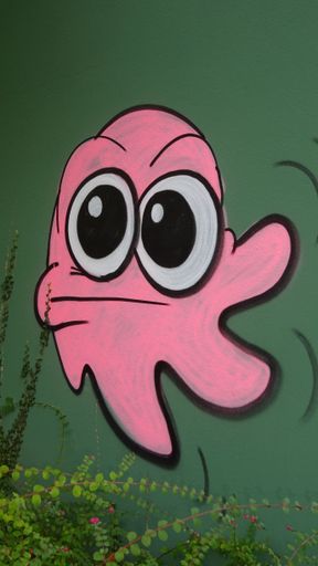 A vertical shot of a painted cute pink octopus graffiti on a green wall