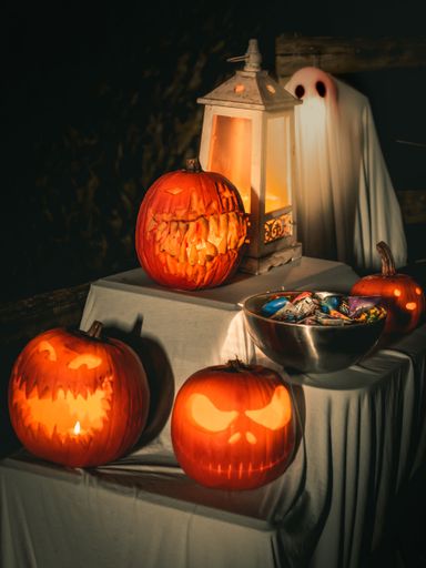 Craved illuminating pumpkins and sweets on the table in he garden at night, Halloween decoration