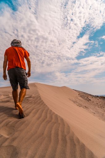 A young man walking with a turban through the desert in Andalucia Spain