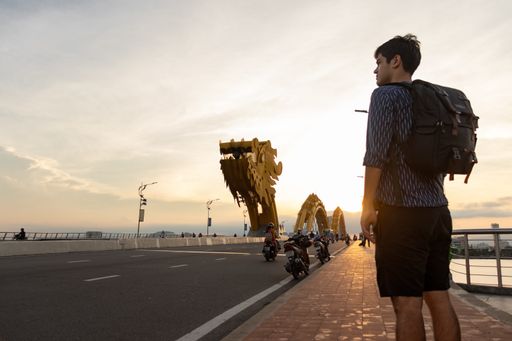 A man standing with a backpack on the Dragon Bridge in Da Nang, Vietnam