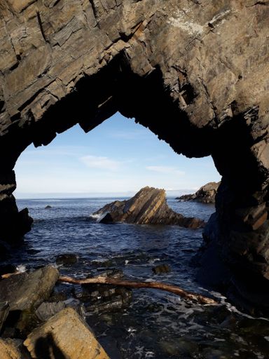 A vertical shot of a stunning view of the sea through a cave in Peterhead