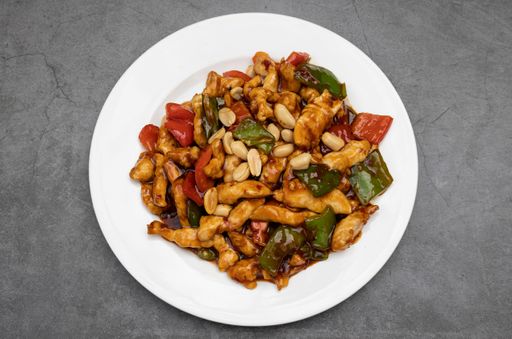 A top view shot of oriental chicken with almonds, chinese traditional food on white plate