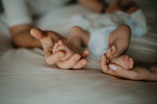 A closeup shot of hands holding a newborn baby's legs
