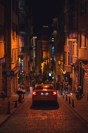 A taxi driving through a narrow dark street in Istanbul during the night, captured from behind